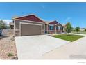 A home with a two-car garage, concrete driveway, and a well-manicured lawn under a clear blue sky at 11129 Paradise Ln, Firestone, CO 80504