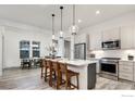 Modern kitchen with stainless steel appliances, quartz countertops, pendant lighting, and an adjacent dining area at 1582 Ash Dr, Erie, CO 80516