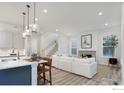 Bright and open living room featuring modern light fixtures, a fireplace, and an adjacent kitchen at 1582 Ash Dr, Erie, CO 80516