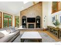 Inviting living room with vaulted ceilings, skylight, and a brick fireplace with built-in shelving at 1900 Eldorado Cir, Superior, CO 80027