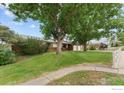 A single story home offers a well-maintained lawn and traditional design, shaded by mature trees at 3400 Erving Ct, Berthoud, CO 80513