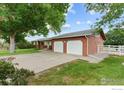 This single-story home features a two-car garage, a well-manicured lawn, and a classic brick exterior at 3400 Erving Ct, Berthoud, CO 80513