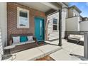 Inviting porch with stylish seating, brick accents, and a vibrant teal door at 4774 Kittredge St, Denver, CO 80239