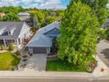 Aerial view of a well-landscaped home with mature trees and a driveway leading to a two-car garage at 591 Brookside Dr, Longmont, CO 80504