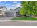 Inviting home featuring a well-maintained lawn, mature trees, and a two-car garage at 591 Brookside Dr, Longmont, CO 80504