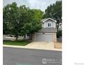 Charming two-story home with mature tree, gray siding, brick accents, and attached two car garage at 6924 Quigley Cir, Firestone, CO 80504