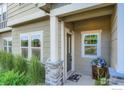 Welcoming townhouse entryway with stone pillar accents, a cozy flower display, and a decorative welcome mat at 876 Winding Brook Dr, Berthoud, CO 80513