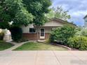 Charming single-story home with brick accents, a well-manicured lawn, and mature landscaping in a suburban neighborhood at 1212 Grant Ave, Louisville, CO 80027