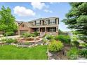 Charming two-story house featuring a lush garden with a serene water feature and a cozy front porch at 15810 E Tall Timber Ln, Parker, CO 80134