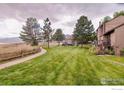 Expansive green backyard, complemented by a paved pathway, and mature trees at 1624 Bradley Ct, Boulder, CO 80305