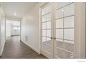 Hallway features hardwood floors and a pair of french doors leading to a well lit room at 1842 Chaffee Crest Dr, Berthoud, CO 80513