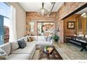Spacious living room with exposed brick, open layout, modern sofa, and views into the kitchen and dining area at 2500 Walnut St # 201, Denver, CO 80205