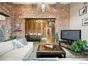 Open living space with brick wall, exposed ductwork, modern lighting, and ample seating arrangement at 2500 Walnut St # 201, Denver, CO 80205
