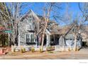 Attractive two-story gray home featuring a welcoming front porch and a well-manicured lawn with a white picket fence at 2765 Meadow Mountain Trl, Lafayette, CO 80026