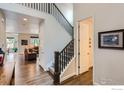 Inviting foyer with hardwood floors, staircase with dark wood railing, and views into the living room at 286 Western Sky Cir, Longmont, CO 80501