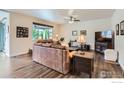 Cozy living room features hardwood floors, large window, ceiling fan, and comfortable leather sofa at 286 Western Sky Cir, Longmont, CO 80501