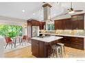 Modern kitchen featuring cherry cabinets, stainless steel appliances, a center island, and eat-in breakfast nook at 400 Lois Dr, Louisville, CO 80027
