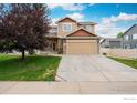 Traditional two-story home with a two-car garage, stone accents, and a well-manicured lawn at 5452 Rustic Ave, Firestone, CO 80504