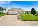 Charming home featuring a two-car garage, well-manicured lawn, and inviting entryway with a cozy garden at 7414 Benton St, Arvada, CO 80003