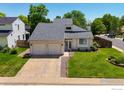 Charming two-story home with well-maintained lawn, landscaped flower bed, and attached two car garage at 7414 Benton St, Arvada, CO 80003
