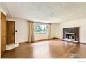 Spacious living room with hardwood floors, a brick fireplace, and lots of natural light at 9449 Schlagel St, Longmont, CO 80503