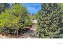 Charming single-story home featuring a brick facade, attached garage, mature trees, and mountain views at 1245 Claremont Dr, Boulder, CO 80305