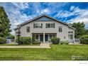 Symmetrical townhome exterior with blue doors, gray siding, and manicured green lawn at 1419 Red Mountain Dr # 126, Longmont, CO 80504