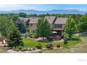 Expansive backyard with a large deck, lush lawn, mature trees, and mountain views at 14652 Kalamath Ct, Westminster, CO 80023
