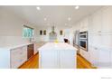 Bright white kitchen with a large center island, stainless steel appliances, and hardwood floors at 14652 Kalamath Ct, Westminster, CO 80023