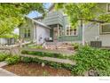 View of the exterior featuring green siding, a cozy front patio, and a white picket fence at 179 Rendezvous Dr, Lafayette, CO 80026