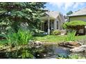 Backyard view with a tranquil pond, lush greenery, and a covered patio area at 203 Springs Dr, Louisville, CO 80027