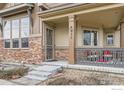 Inviting front porch featuring stone columns and a cozy seating area, perfect for relaxing outdoors at 555 Gallegos Cir, Erie, CO 80516