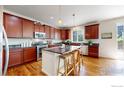 Spacious kitchen with wooden cabinets, a granite-topped island with seating, and modern stainless steel appliances at 6358 Union Ave, Firestone, CO 80504