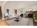 Cozy living room featuring a comfortable sofa, fireplace, and large window, perfect for relaxation at 6864 Balsam St, Arvada, CO 80004