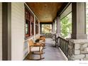 Spacious covered porch with comfortable rocking chairs, wood railings, and stone pillars at 1108 Grant Ave, Louisville, CO 80027