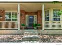 Inviting front porch with brick columns, stylish lighting, and decorative flower pots at 13951 Brookside Ct, Broomfield, CO 80023