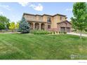 Two-story house with landscaped front yard and a mix of stone and siding at 1485 Eversole Dr, Broomfield, CO 80023