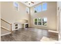 Open-concept living room with hardwood floors, high ceilings, a fireplace, and large windows at 17216 E Trailmaster Dr, Parker, CO 80134