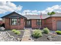 Inviting brick home with a well-maintained front yard, stone pathway, and charming front entrance at 1806 Crestone Ct, Longmont, CO 80504