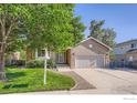 Charming brick home featuring a manicured lawn, mature trees, and a two-car garage at 2615 Falcon Dr, Longmont, CO 80503