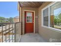 Cozy balcony features neutral siding, a bright red door, and railing with street views at 3009 Madison Ave # 317, Boulder, CO 80303