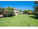 Expansive backyard with lush green grass, mature trees, and ample space for outdoor activities at 4804 Kingbird Dr, Frederick, CO 80504