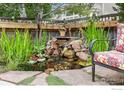 Relaxing backyard garden featuring a beautiful waterfall feature, lush plants, and inviting seating area at 6324 Saratoga Trl, Erie, CO 80516
