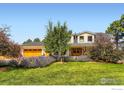 Inviting two-story home featuring a lush front lawn, colorful flowerbeds, and a charming double-door entrance at 6709 Walker Ct, Niwot, CO 80503