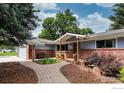 Inviting front entry with brick archway, covered porch, and landscaped garden beds at 7459 Mount Meeker Rd, Longmont, CO 80503