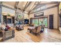 Spacious living room with vaulted ceilings, exposed beams, stone fireplace, and wood floors at 8576 Niwot Meadow Farm Rd, Niwot, CO 80503