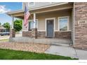 Inviting front porch with stone pillars and American flag adds charm to this lovely home at 108 Wake St, Frederick, CO 80530
