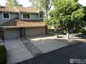 Two-story townhouse featuring a two-car garage, a brown roof and lovely landscaping surrounding the driveway at 12183 W Chenango Dr, Morrison, CO 80465