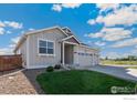 Charming single-story home boasts a three-car garage and well-manicured front yard with blue sky at 338 Lemonade Dr, Berthoud, CO 80513