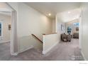 Upstairs hallway area featuring carpet flooring, bright walls and a view to an open living area at 338 Lemonade Dr, Berthoud, CO 80513